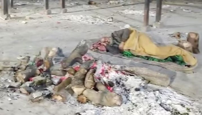 उत्तर-प्रदेश: कंपकपाती ठण्ड के बीच जलती चिता के बगल में बिस्तर लगाकर नींद पूरी कर रहे बुजुर्ग का Video वायरल होने के बाद सरकारी अमले की टूटी नींद 